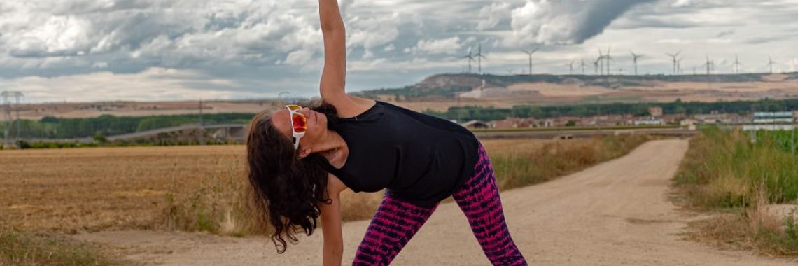 Outdoor fitness scene of a woman stretching on a dirt path in Soto de Cerrato amidst scenic landscapes.